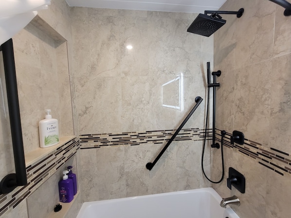 A modern bathroom with a bathtub, a shower, and a vanity with a mirror.