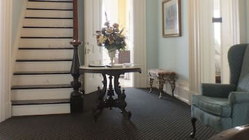 A staircase leading to a door, a chandelier, a table with a vase, and a chair.