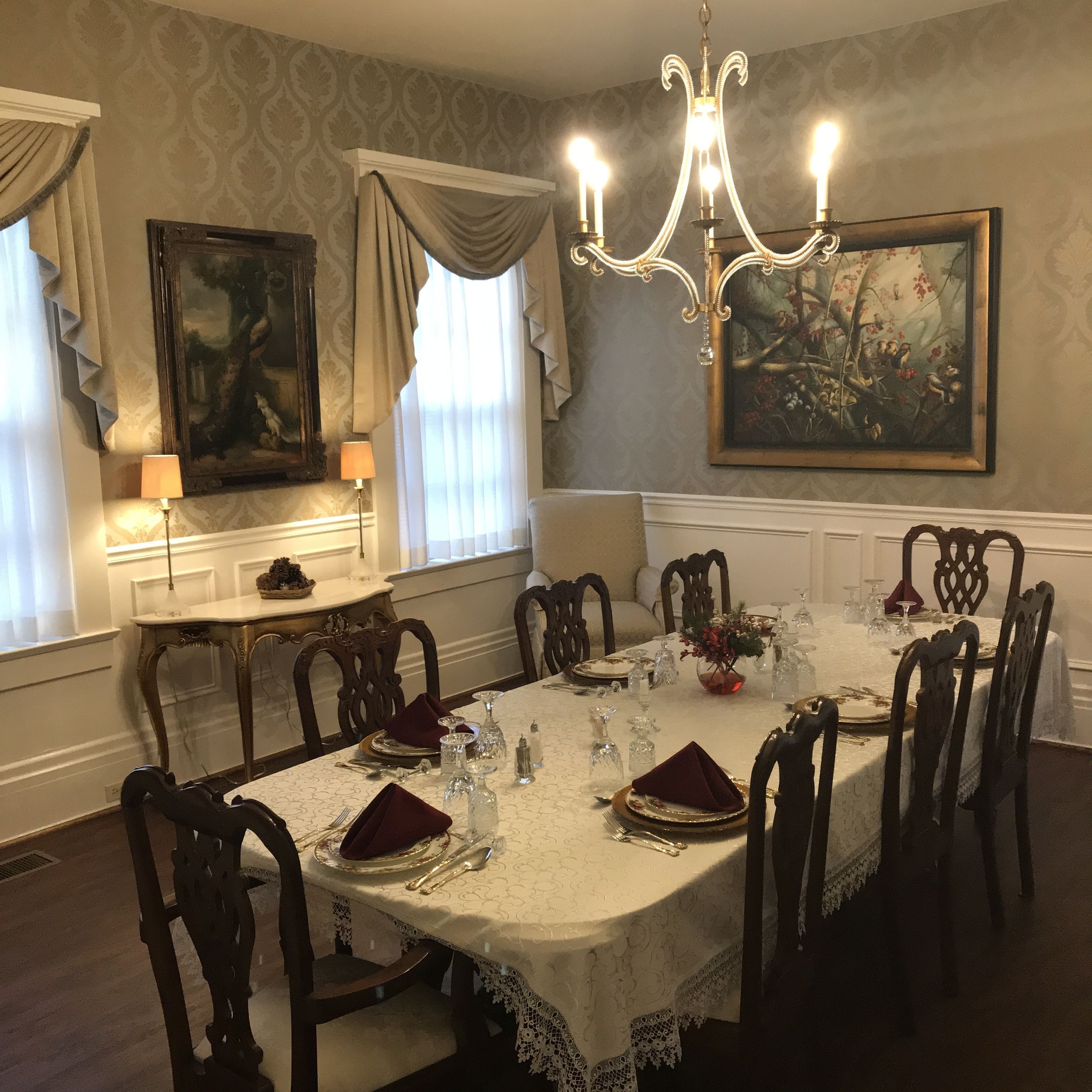 A formal dining room with a long table set for a meal, surrounded by wooden chairs.