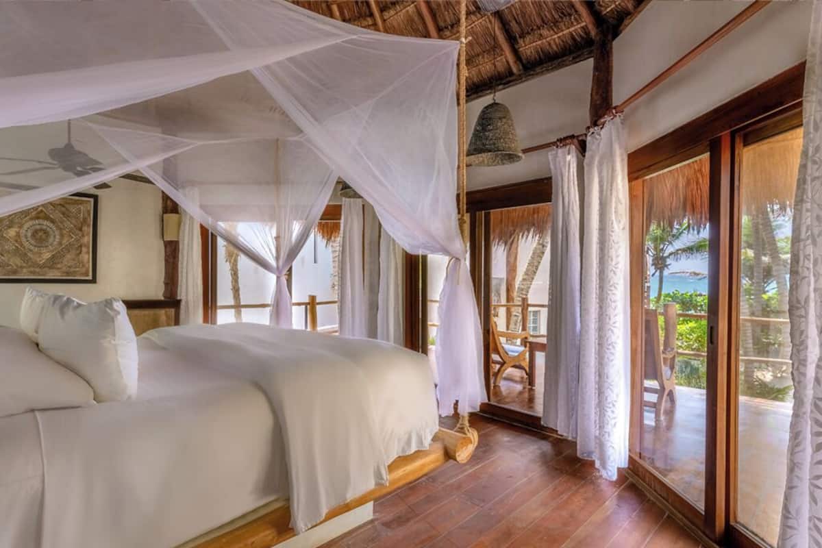 Un dormitorio con cama, piso de madera y vista al exterior.