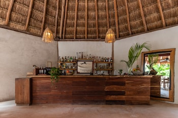 Relax with a drink at our bar, featuring a rustic wooden bar, pendant lights, and a cozy atmosphere. at Encantada Tulum