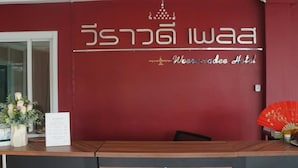 Un mostrador de recepción con una pared color borgoña y una encimera de madera.