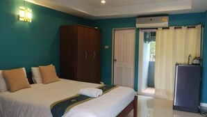 Habitación de hotel con una cama grande, un armario, un escritorio y una puerta que da a un balcón.