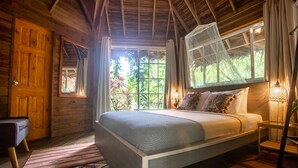 Una habitación de madera con una cama, una silla y un ventanal.