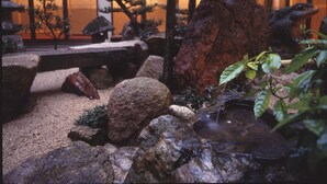 Un jardin japonais traditionnel, avec des rochers, un petit étang et des arbres bonsaï.