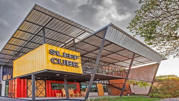 A modern building with a prominent yellow sign reading "SLEEP CUBE". - Sleep Cube (Khon Kaen)