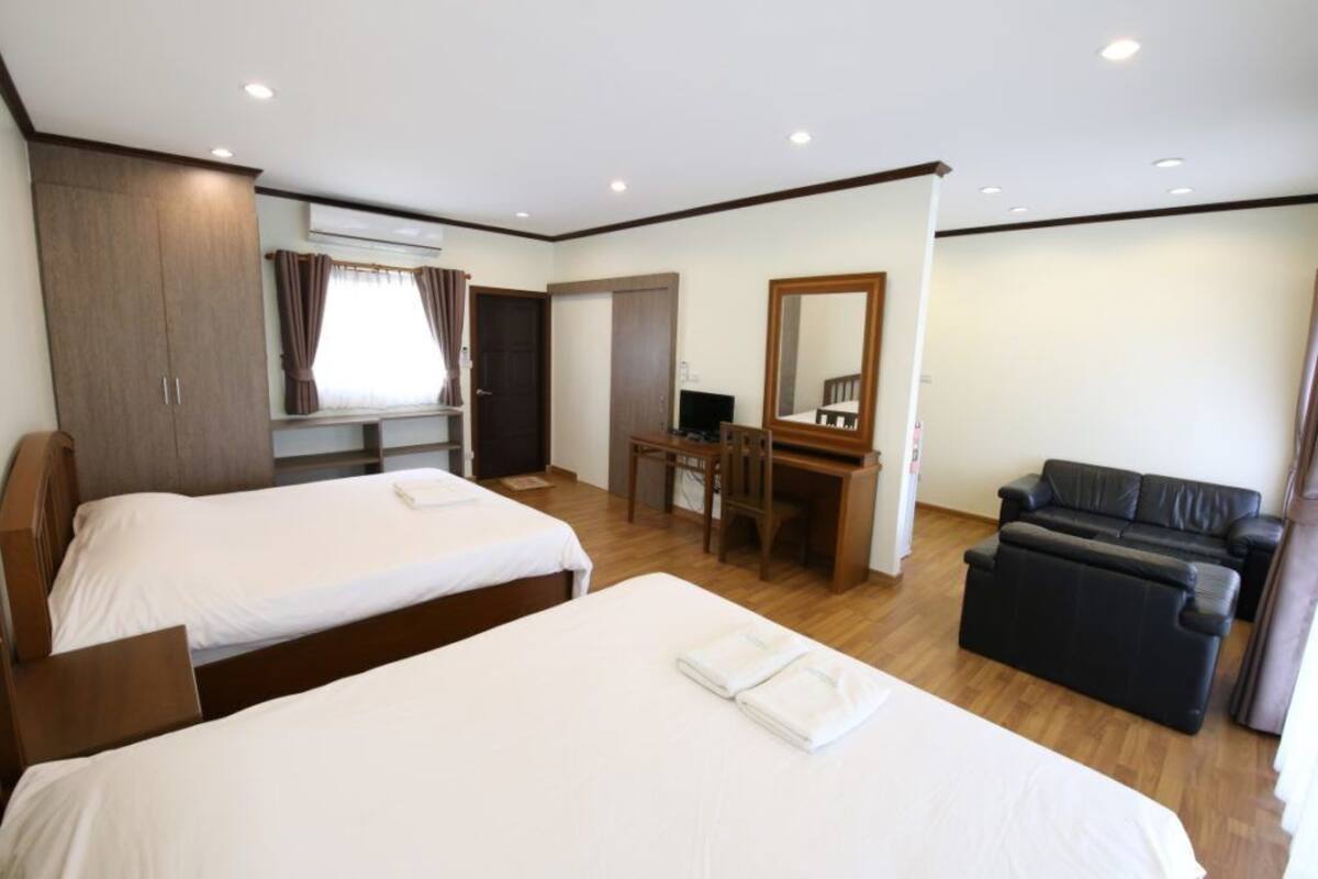 Une chambre d’hôtel avec deux lits, un bureau, un ordinateur, un canapé et un miroir.