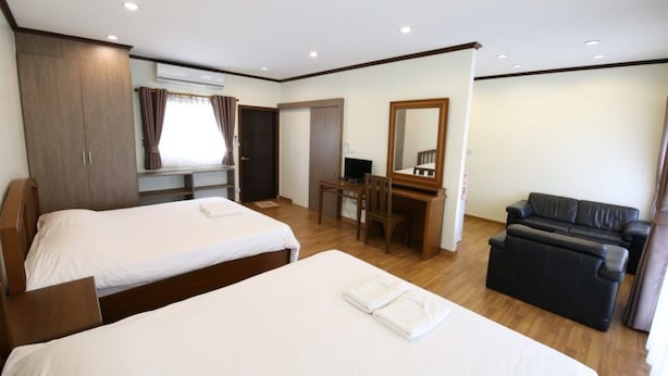 Une chambre d’hôtel avec deux lits, un bureau, un ordinateur, un canapé et un grand miroir.
