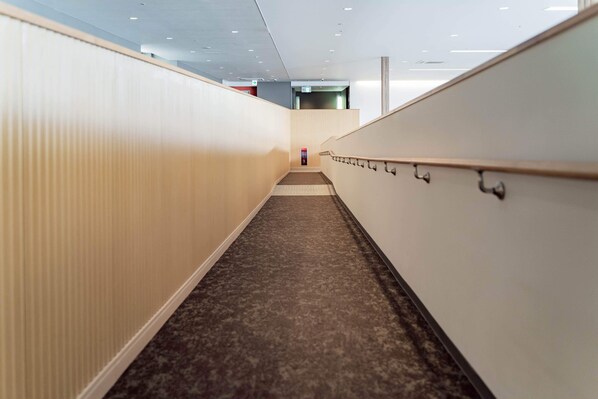 A modern interior corridor with a carpeted floor, white walls, and a handrail on the right. - Kansai International Airport Hotel 11 (Tajiri)