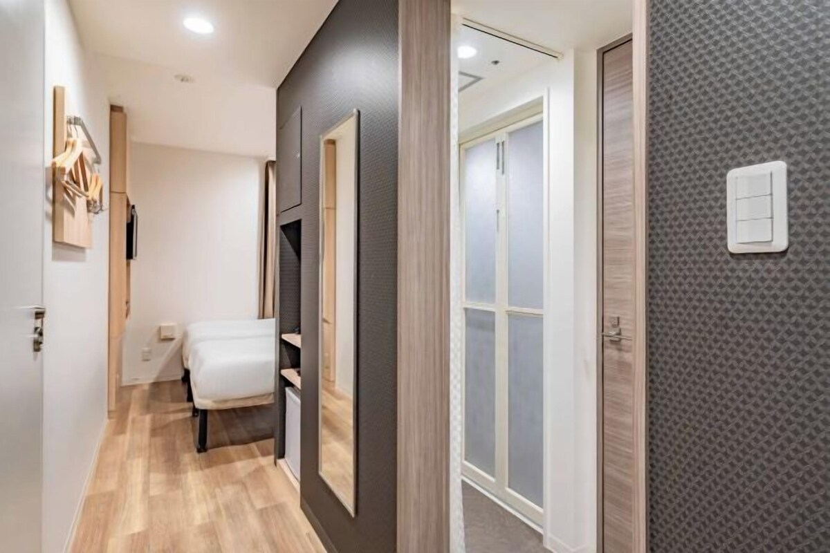 Un pasillo con una cama, un armario y una puerta que da a una habitación.