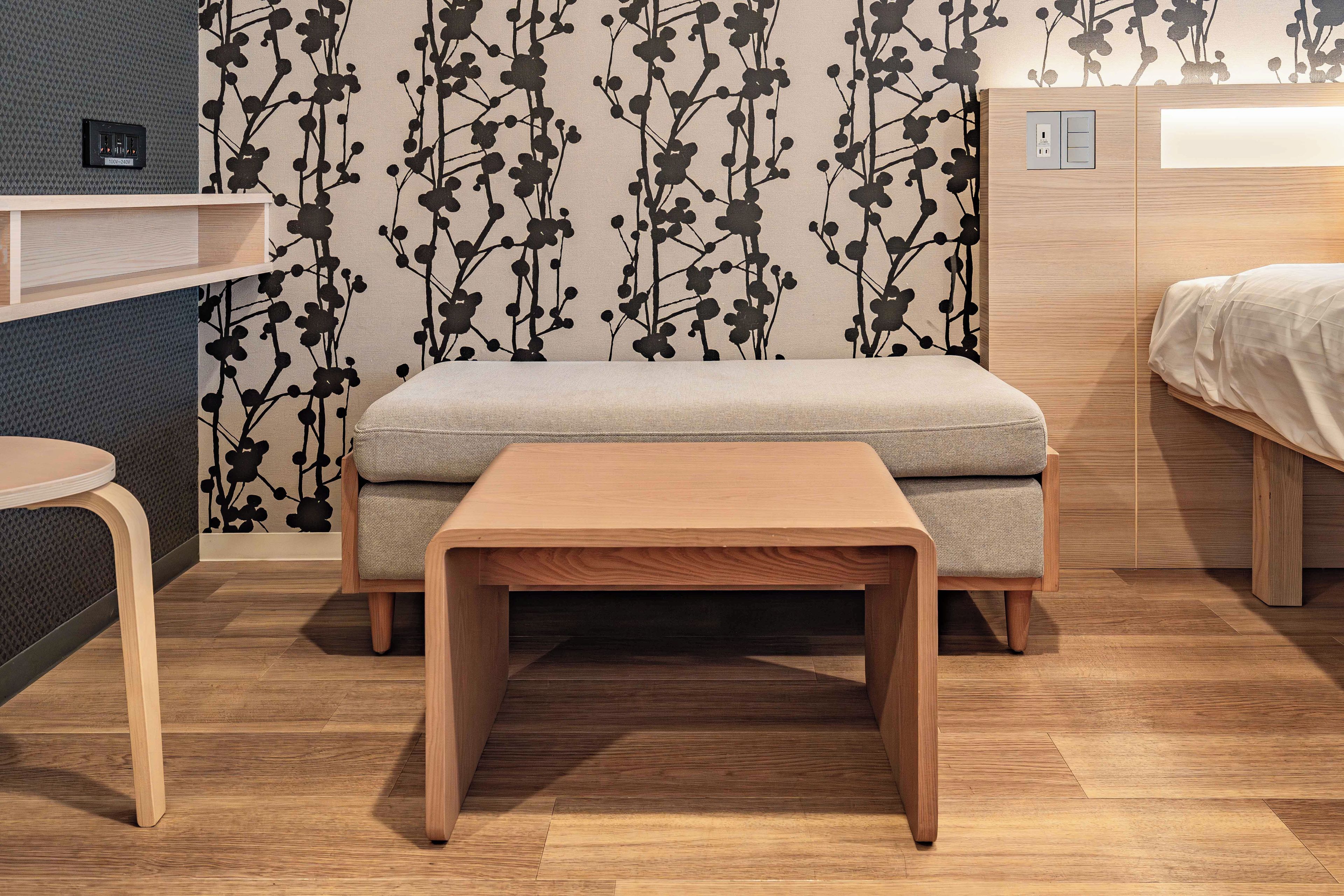 Una habitación pequeña con cama, una mesita y un banco.
