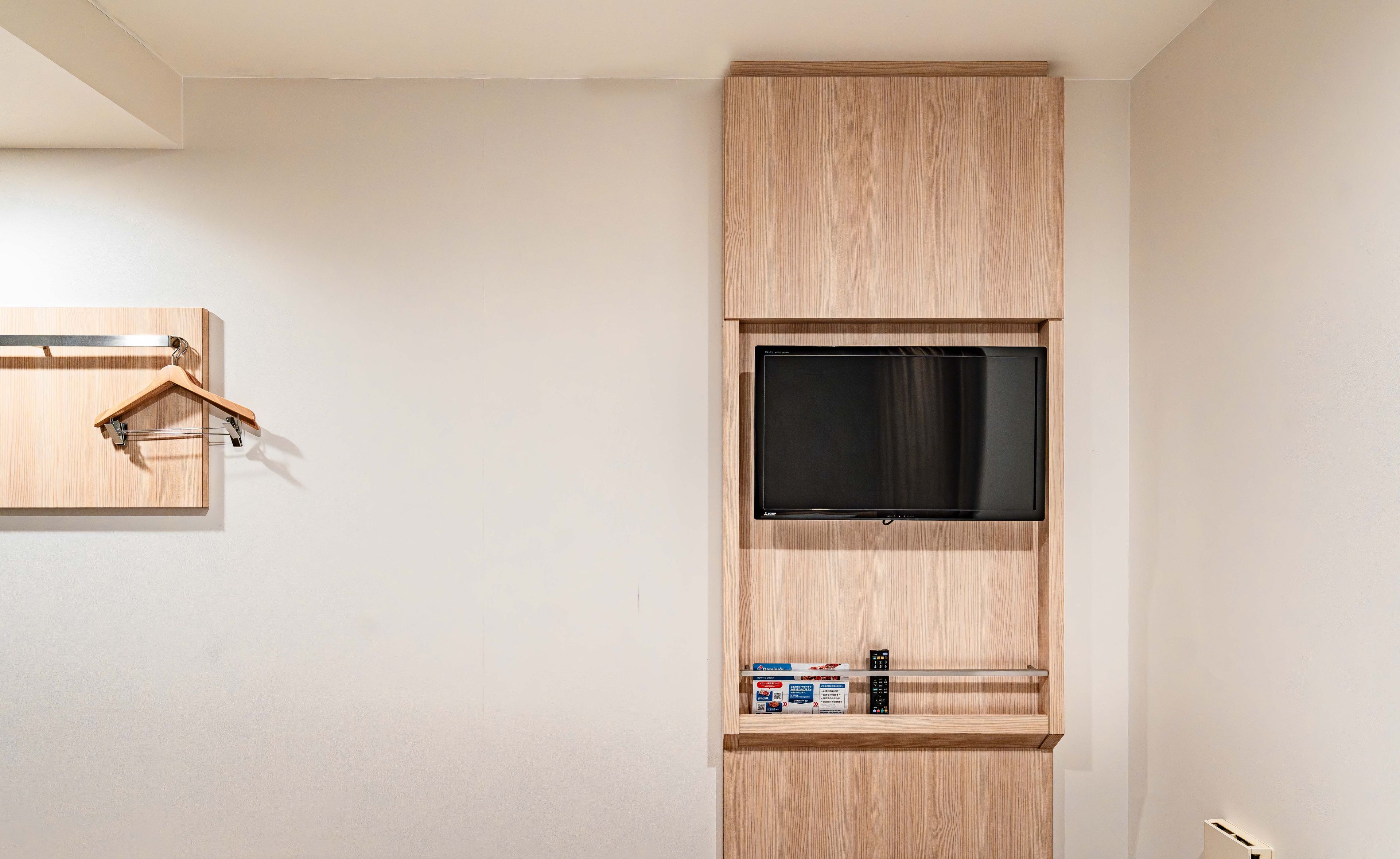 Una habitación con estante para televisión empotrado, un armario de madera y un perchero.