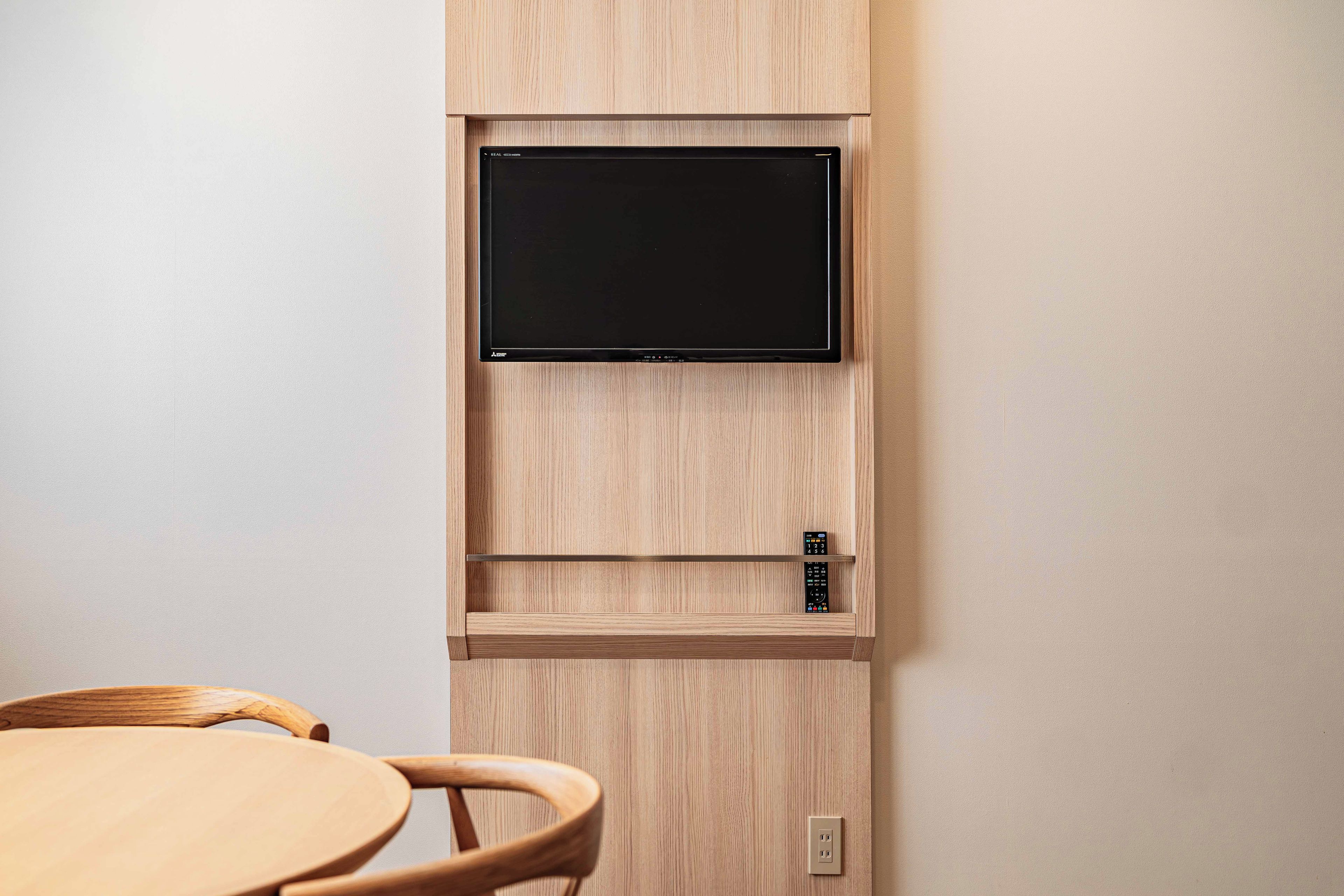 Un televisor montado en la pared con un cajón para el control remoto debajo.