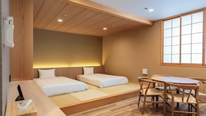 Ein Hotelzimmer mit zwei Betten, einem Holztisch und einem großen Fenster.