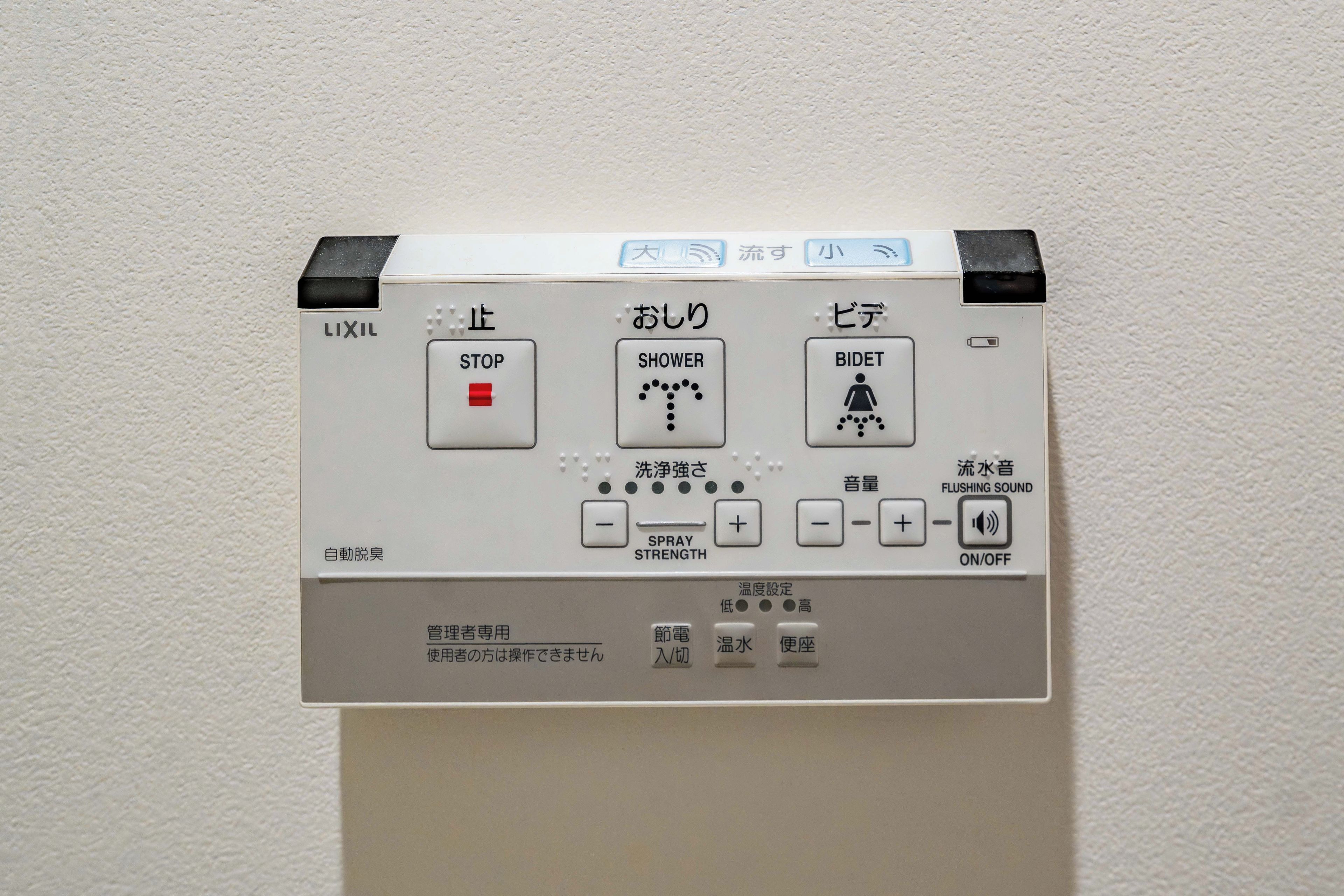 A control panel with buttons labeled 'STOP,' 'SHOWER,' and 'BIDET,' along with a 'SPRAY STRENGTH' adjustment and a 'FLUSHING SOUND' toggle.