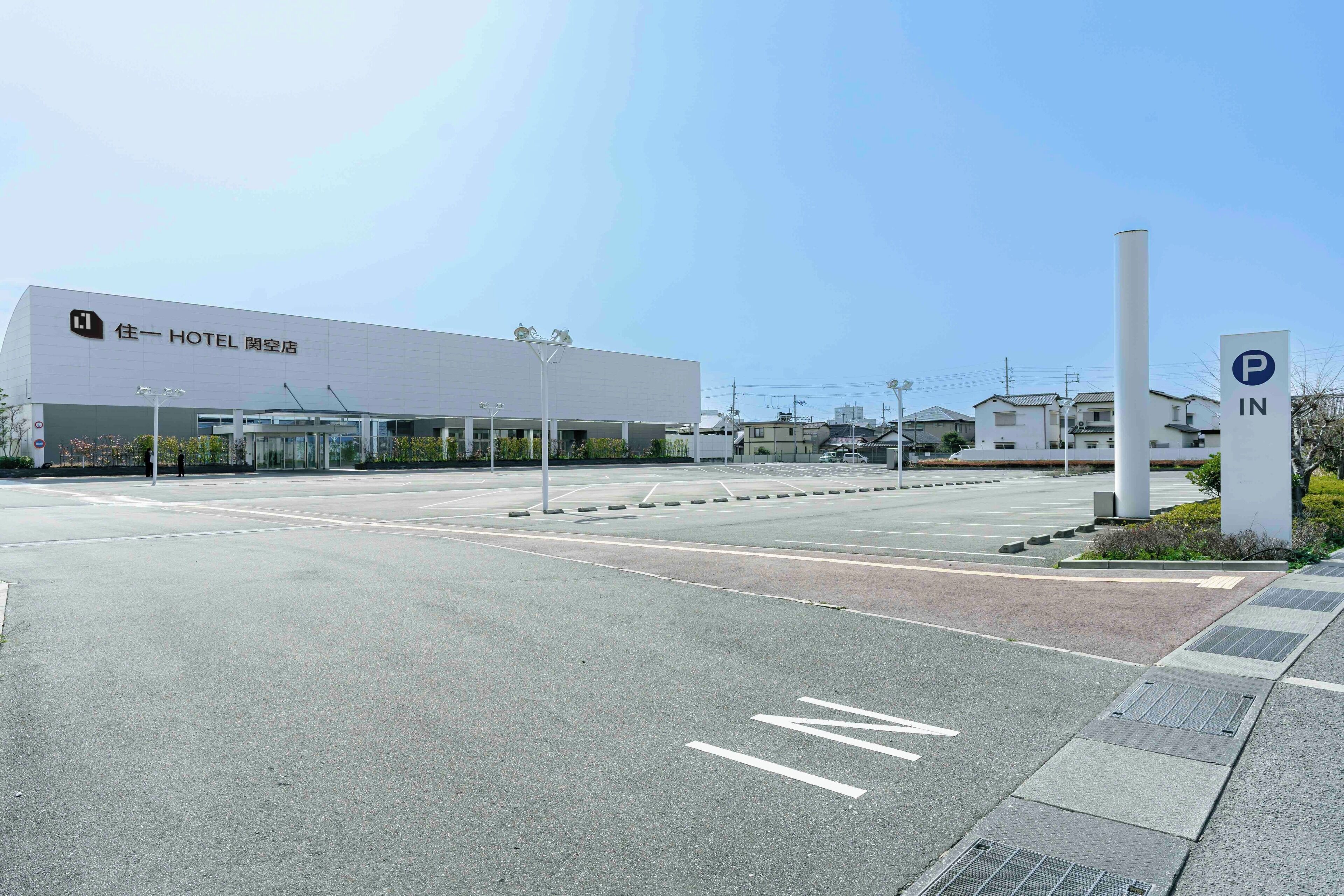 A modern hotel with a large parking area and a clear sky.