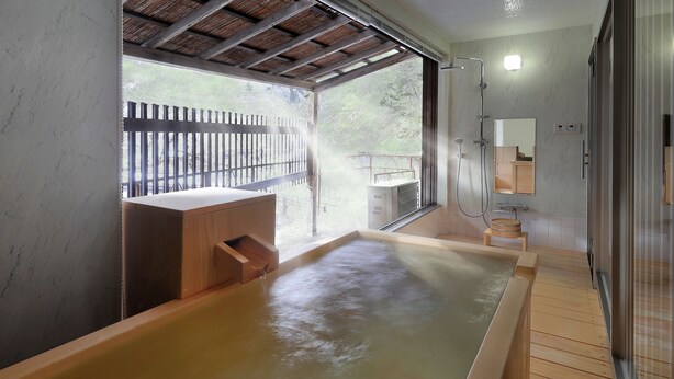 Un área de spa con una bañera de hidromasaje de madera, un banco de madera y un box de ducha de vidrio.