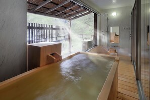 Un área de spa con una bañera de hidromasaje de madera, un banco de madera y un box de ducha de vidrio.