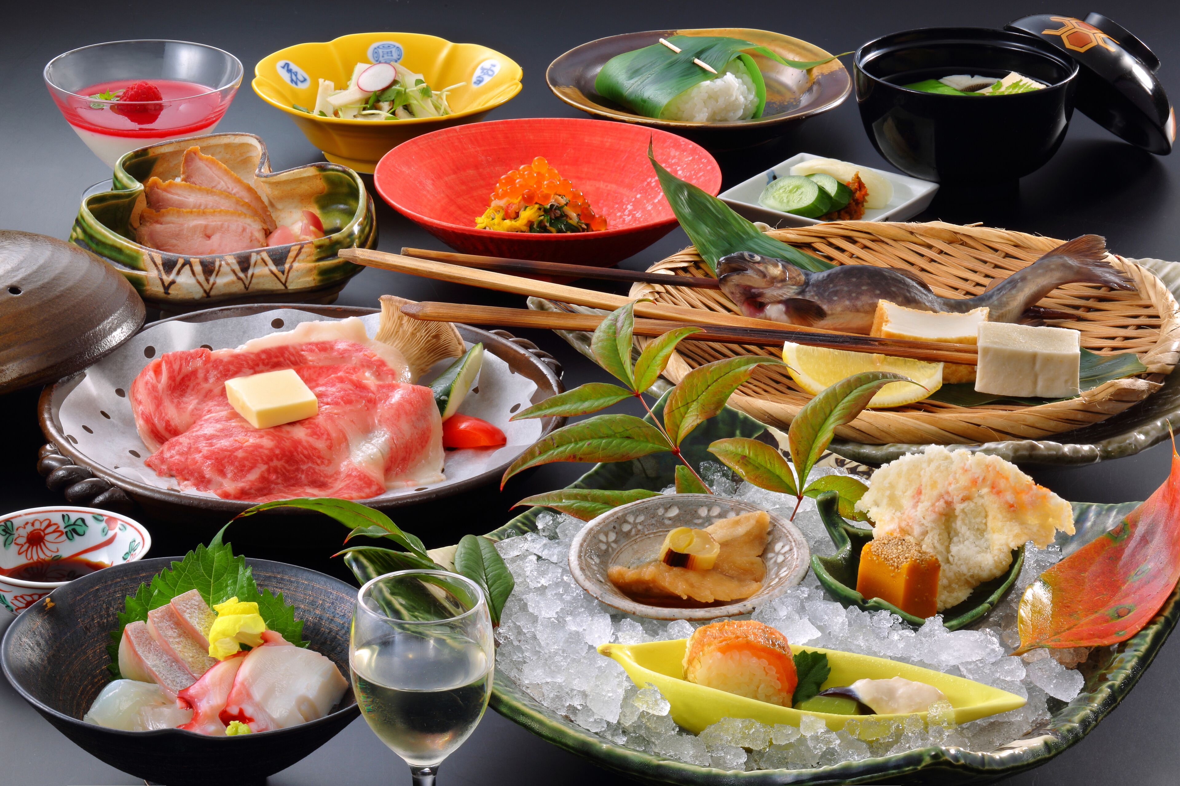 A variety of Japanese dishes arranged on a table with ice, including sushi, sashimi, and other seafood items.