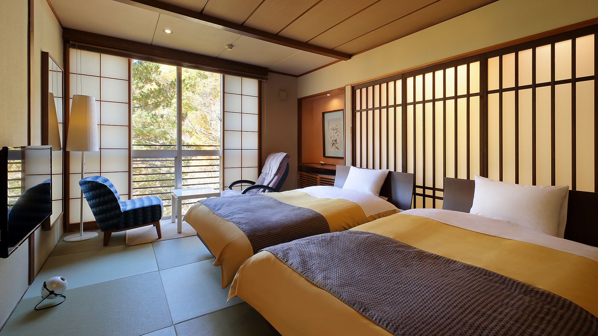 Une chambre d’hôtel avec deux lits, une chaise, un bureau et un téléviseur.