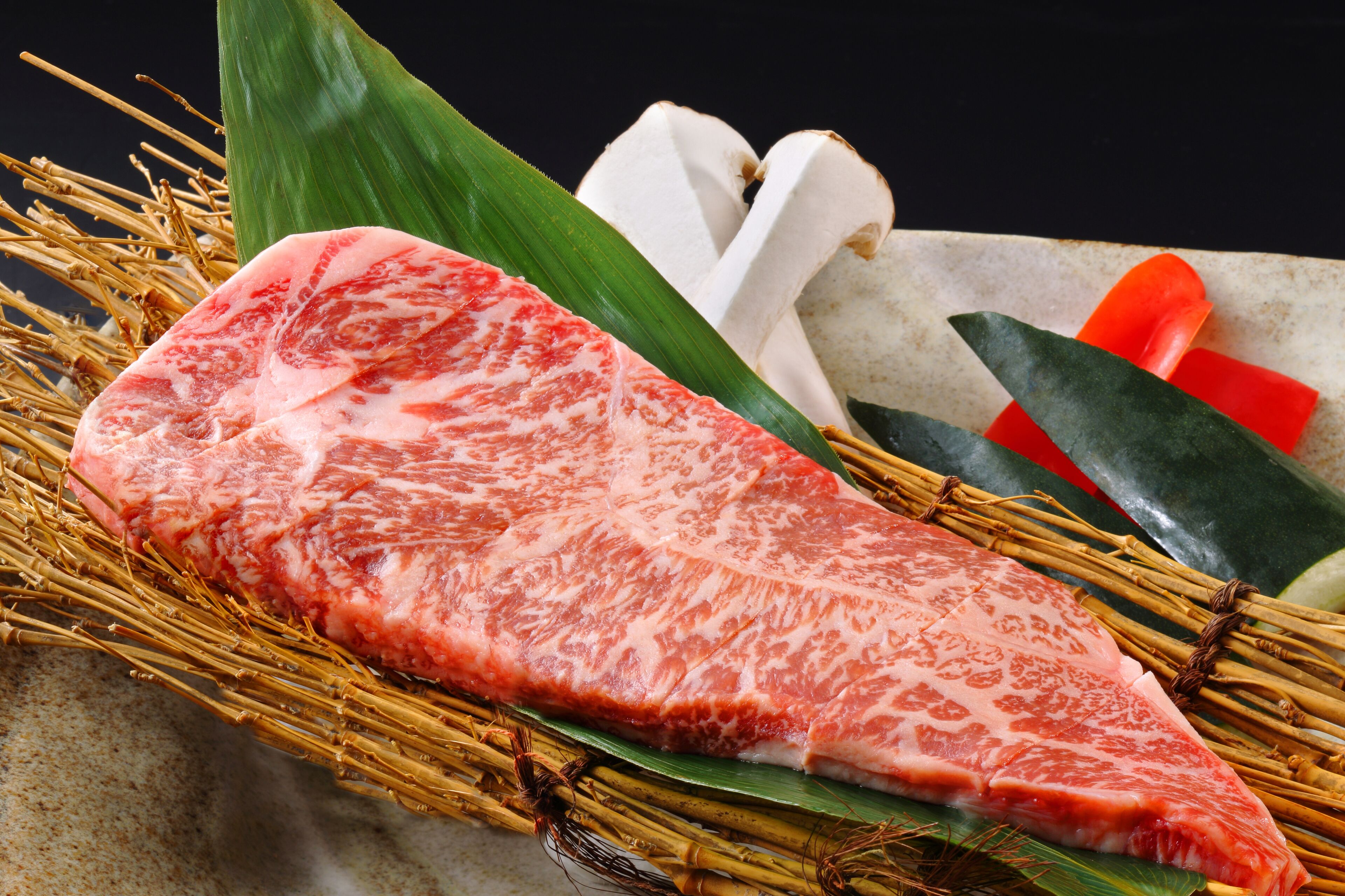 A raw steak with a knife and bamboo sticks.