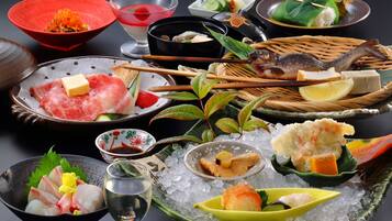 Diversos pratos japoneses, como sashimi, sushi e tempura, servidos sobre gelo com hashis e pequenas tigelas.