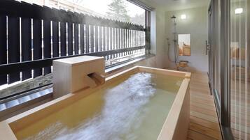 Un baño moderno con una bañera de madera, cabina de ducha de vidrio y vistas al exterior.