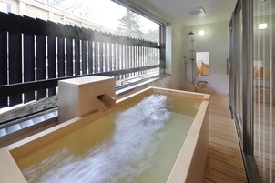 Un baño moderno con una bañera de madera, cabina de ducha de vidrio y vistas al exterior.