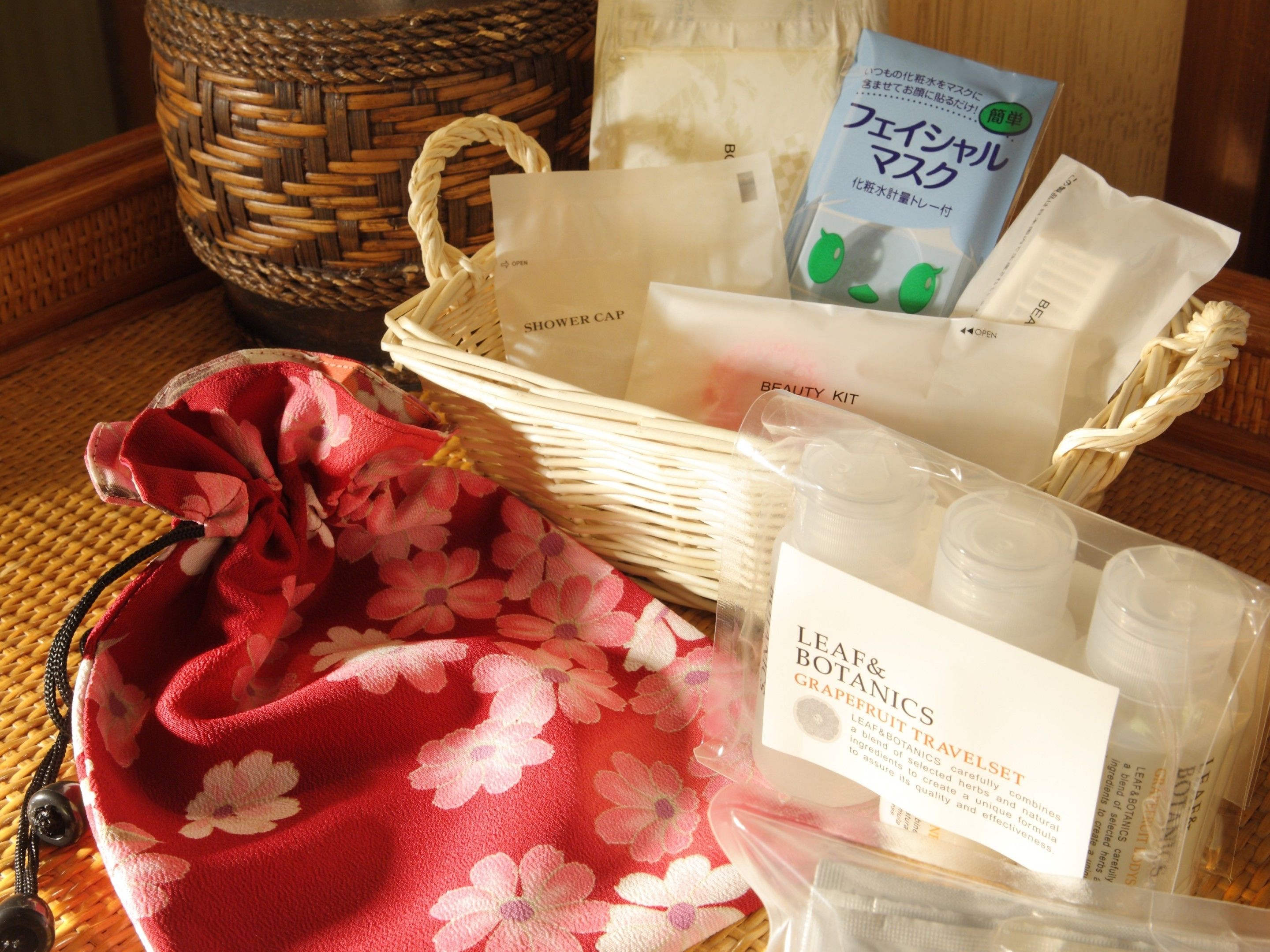 A basket with a floral bag, a beauty kit, and some botanical products.