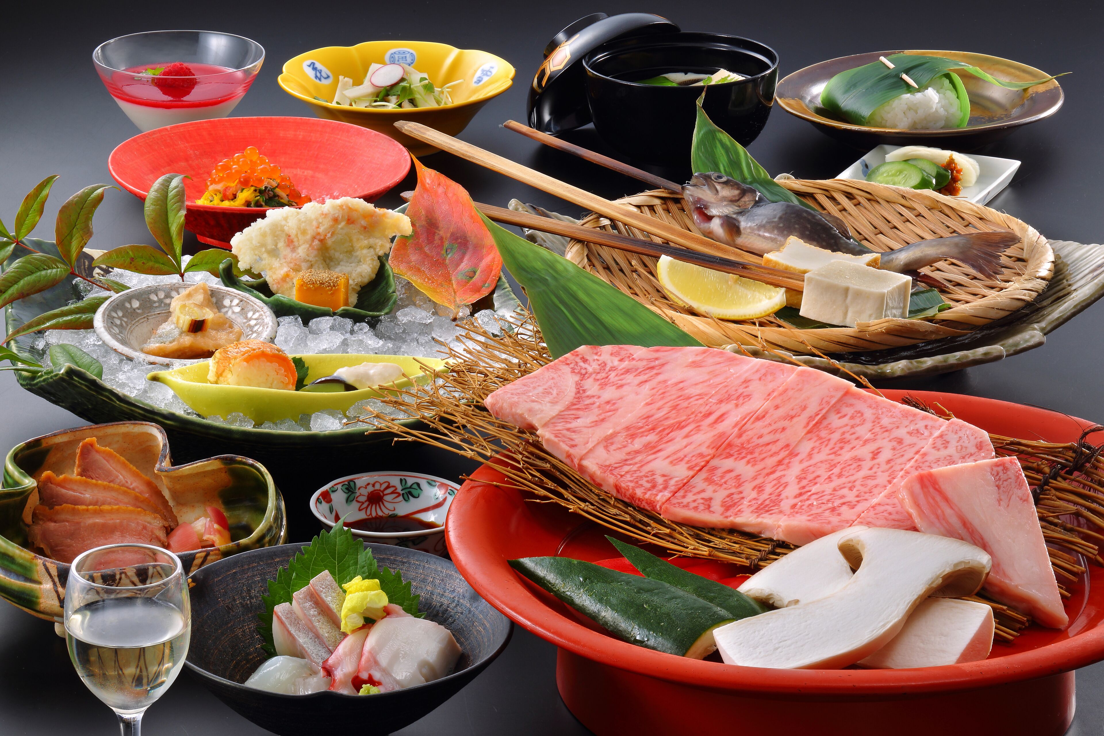 Variedad de platos japoneses, como sashimi, sushi y tempura, dispuestos sobre una mesa con hielo y adornos.