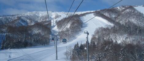 A snowy mountain road with a ski lift and power lines.