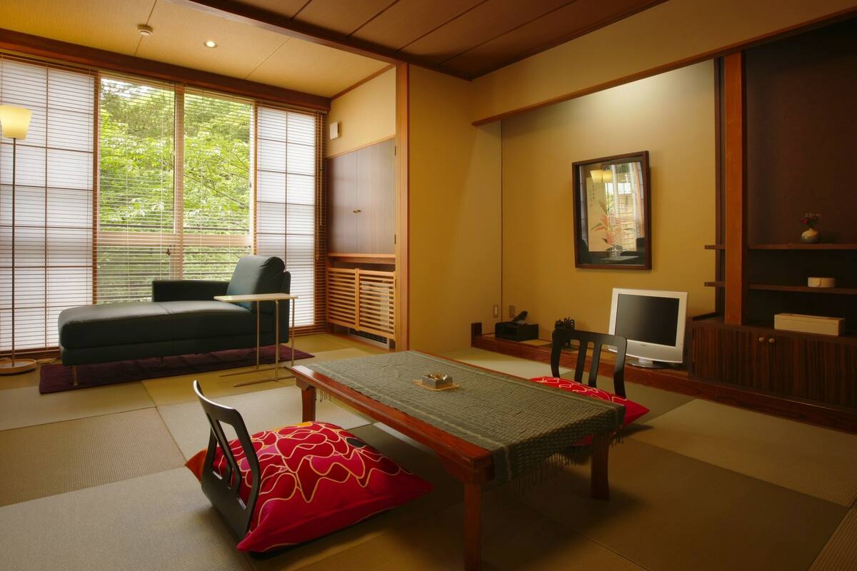 Ett traditionellt japanskt rum med tatamimattor på golvet, ett lågt bord och en soffa.
