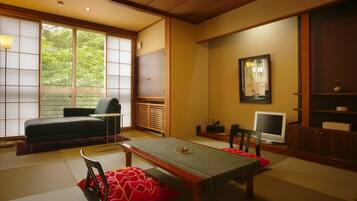 A traditional Japanese-style room with tatami flooring, a low table, and a sofa.