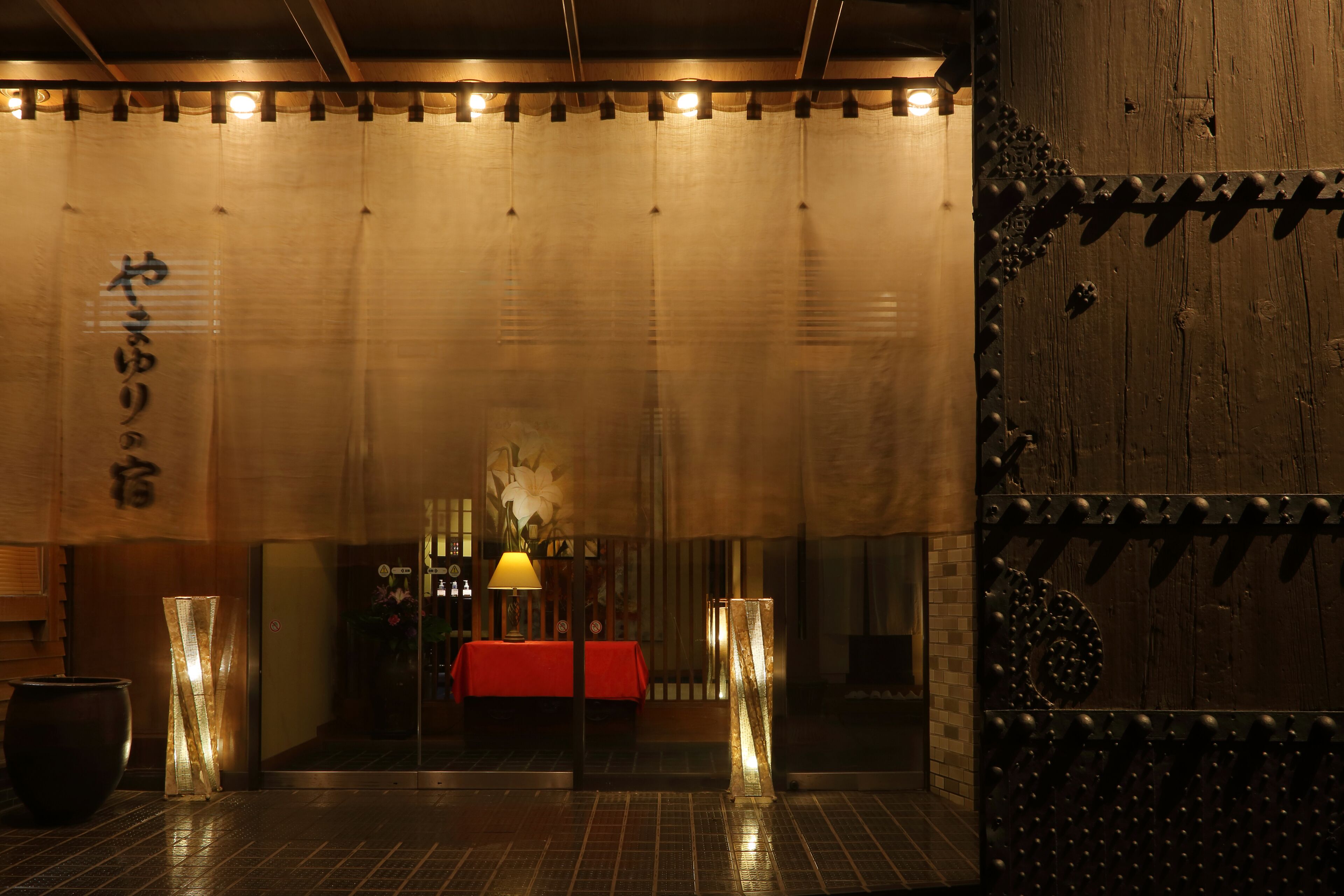 A traditional Japanese room with tatami flooring, a low table with a red tablecloth, and a shoji screen with Japanese calligraphy.