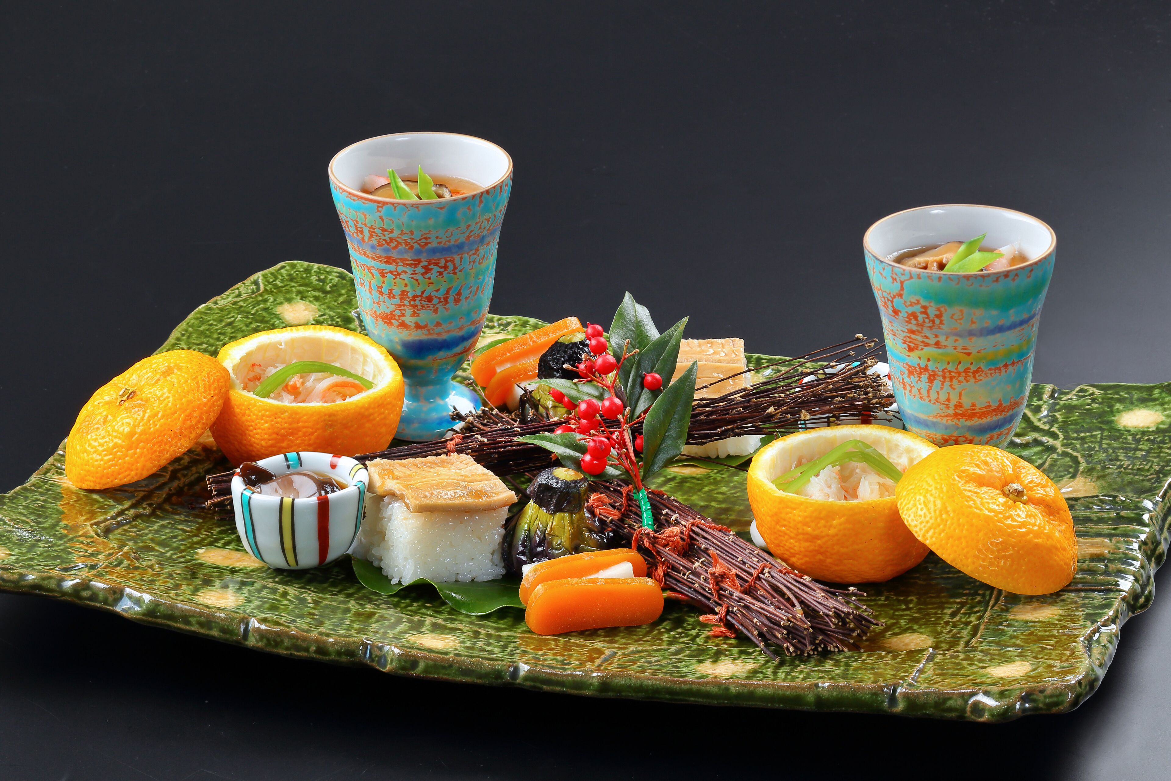 A tray with food and drinks, including oranges, a bowl of rice, and two cups with a blue pattern.
