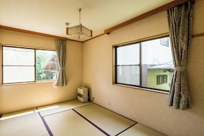 Traditional Japanese-style room with tatami flooring, large windows, and a simple layout.