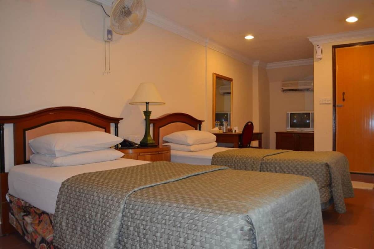 Une chambre d’hôtel avec deux lits simples, une table de chevet avec une lampe, un miroir, une télévision et un appareil de climatisation.