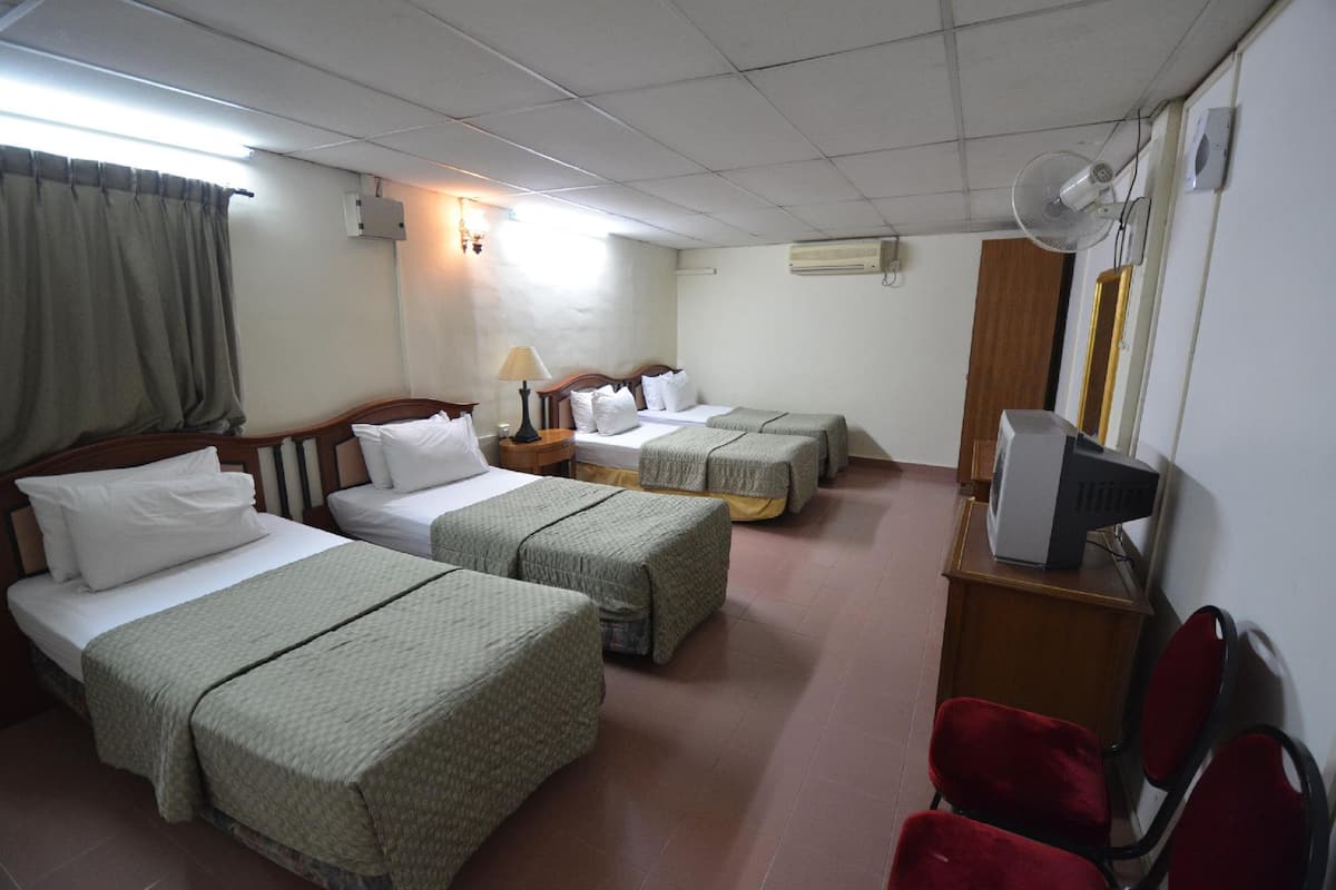 Une chambre d’hôtel avec deux lits, un bureau avec un ordinateur, une télévision et une chaise rouge.