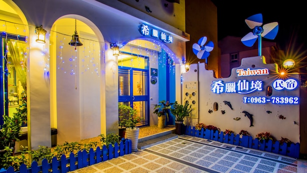 A hotel entrance with a blue archway, illuminated string lights, and a blue fence.