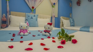 A bedroom with two beds, a blue wall, and Hello Kitty plush toys.