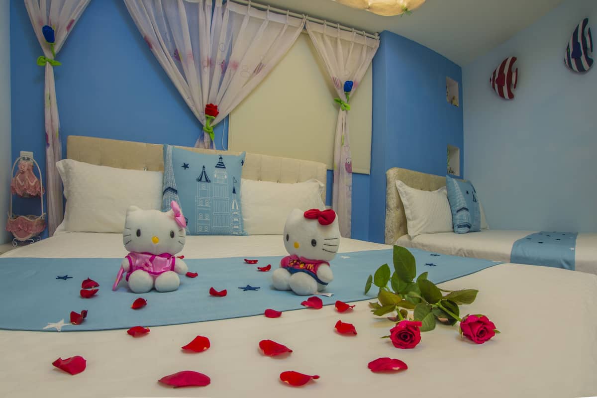 A bedroom with two beds, a blue wall, and Hello Kitty plush toys.