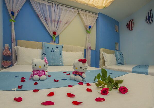 A bedroom with two beds, a blue wall, and Hello Kitty plush toys.
