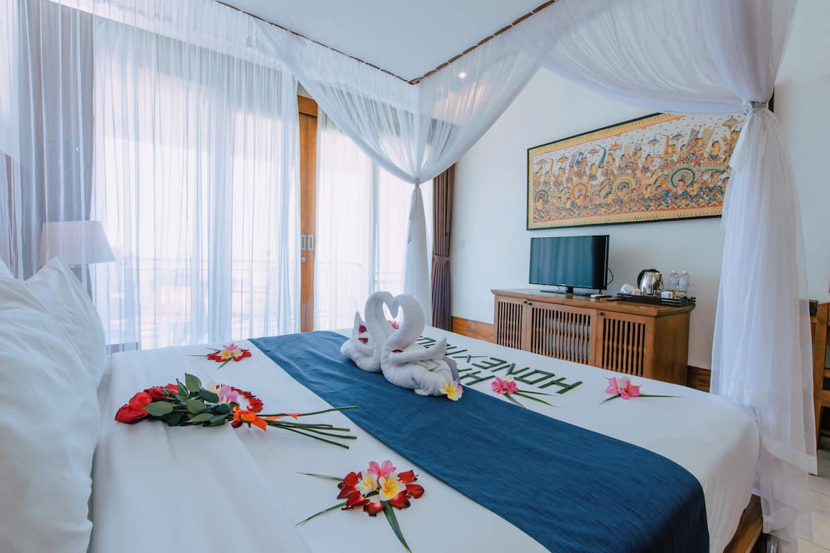 A hotel room with a bed, a television, a wooden cabinet, and a large decorative painting on the wall.