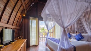 A bedroom with a wooden ceiling, a bed with white and blue bedding, a TV on a wooden table, and a balcony with curtains. - Puri Pandawa Resort (Kutuh)