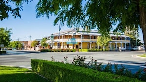 A two-story hotel with a balcony on the second floor, a signboard, and a well-maintained lawn in front. - Boorowa Hotel (Boorowa)