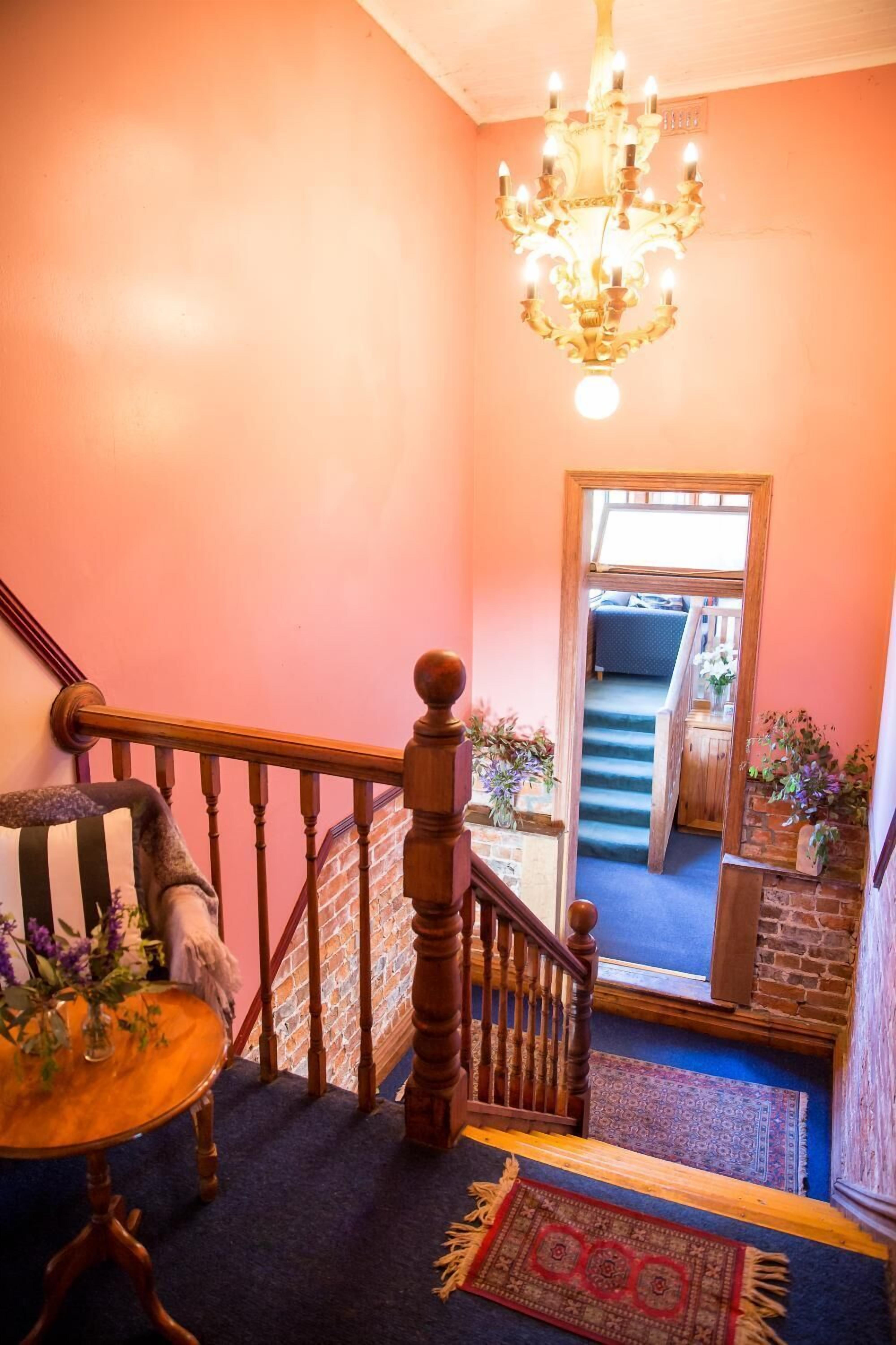 A staircase with a wooden handrail and a chandelier.
