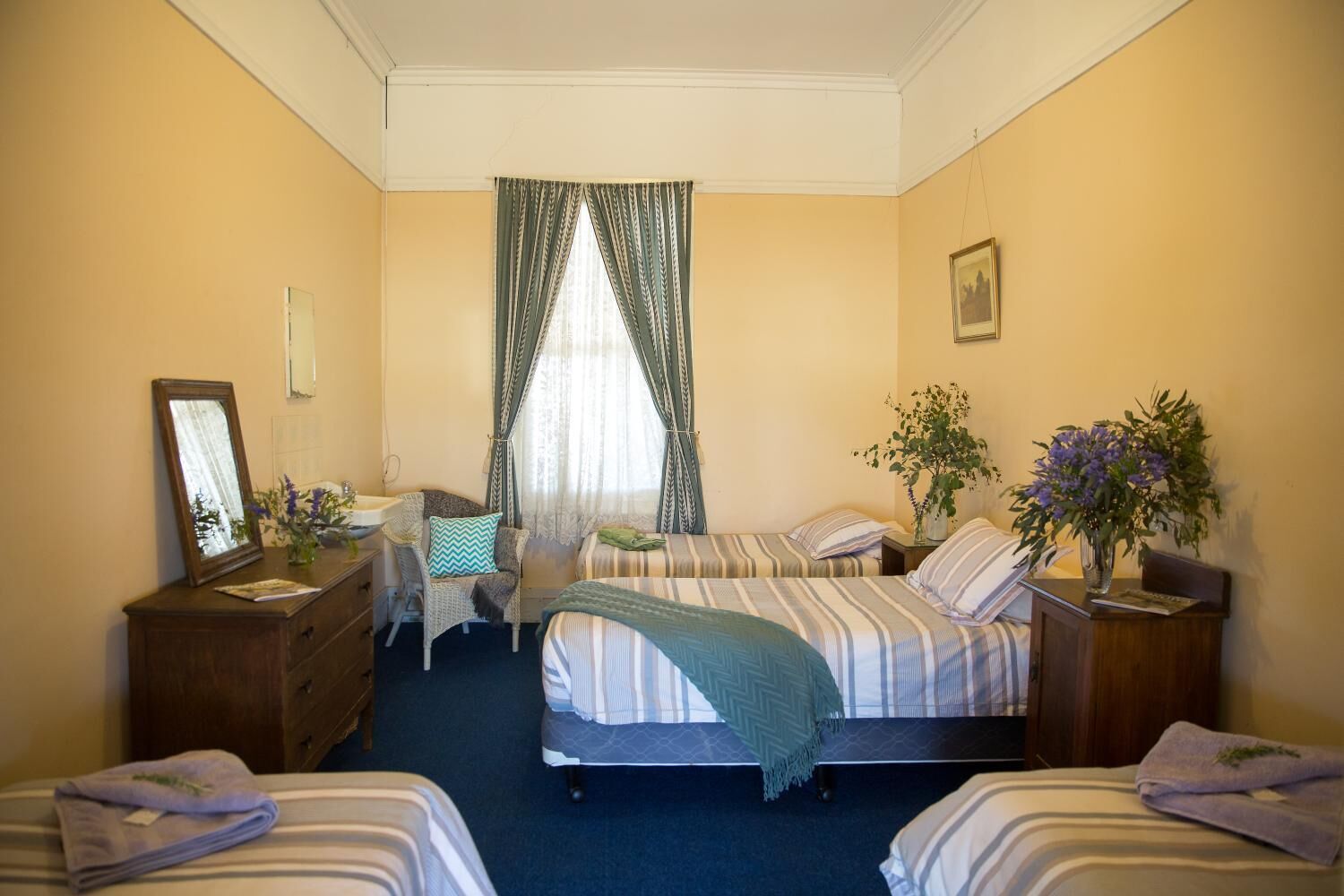 A hotel room with two beds, a desk, a chair, a mirror, and a window with curtains.