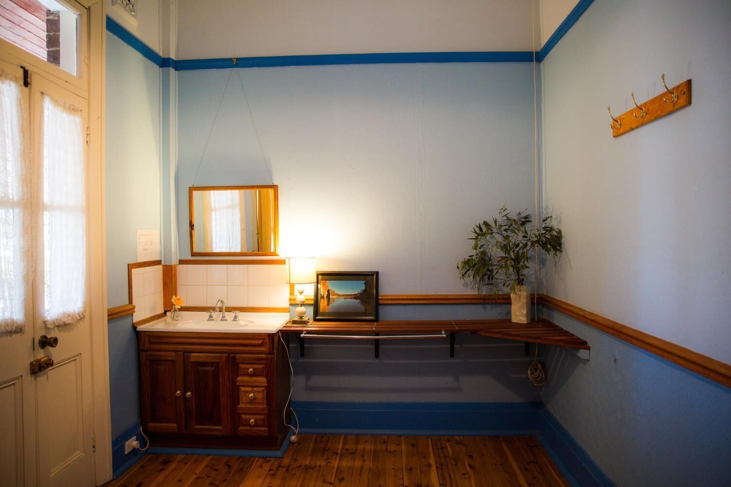 A bathroom with a wooden vanity, a mirror, a sink, a bench, and a potted plant.