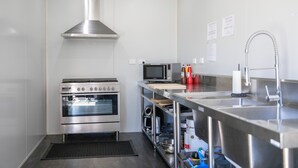 Una cocina moderna con electrodomésticos de acero inoxidable, incluyendo horno y microondas, además de un lavabo con grifo.