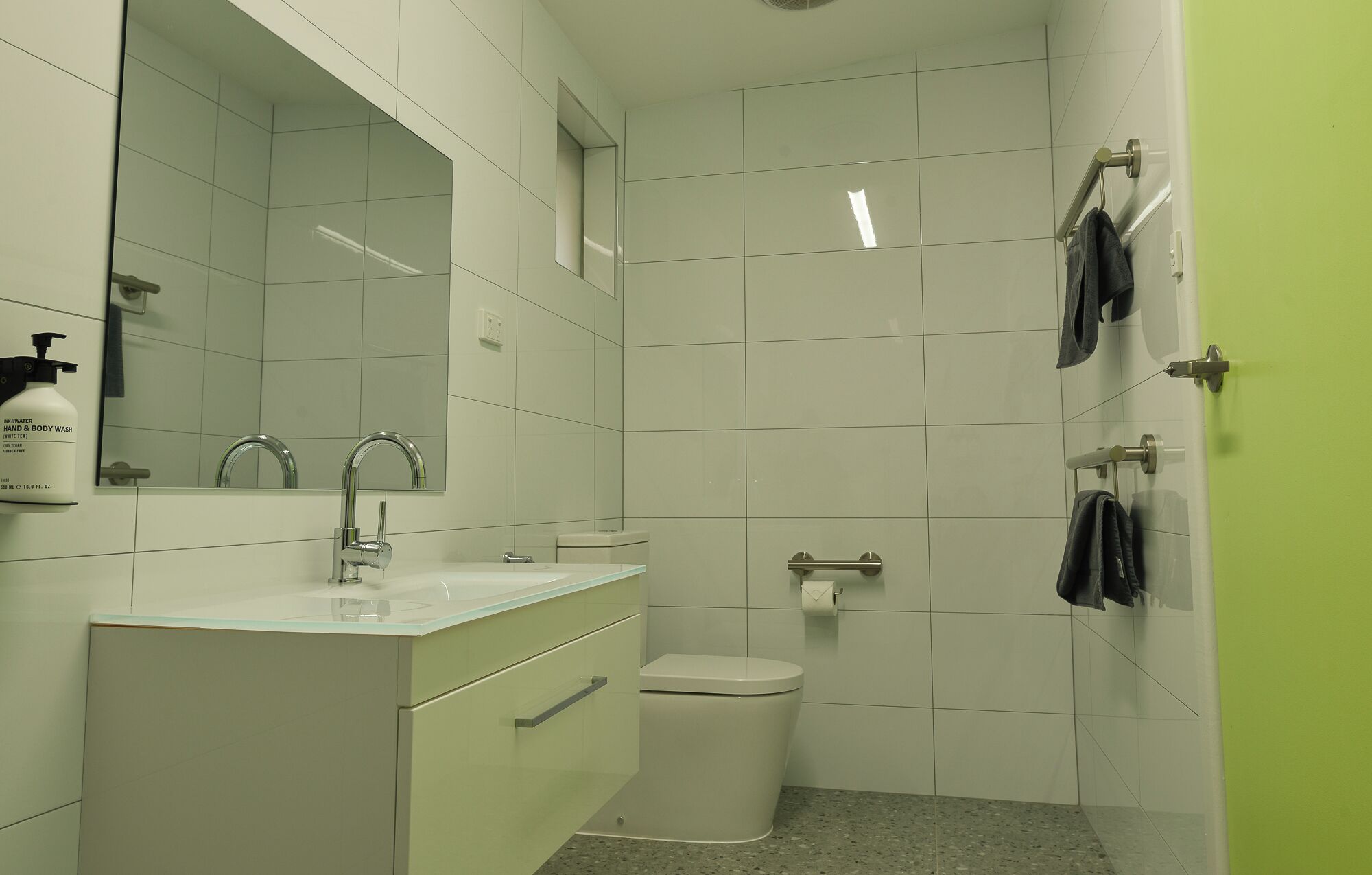 A bathroom with a white sink, mirror, toilet, and a towel rack.